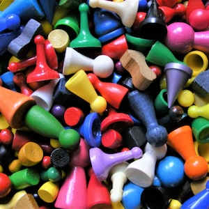 May include: A vibrant assortment of colorful game pieces, including pawns and other shapes, in shades of red, blue, green, yellow, and more. The pieces are made of wood and plastic, creating a playful and engaging visual.
