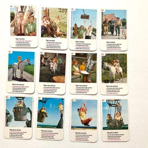 Op de afbeelding: Een verzameling vintage ruilkaarten met kleurrijke illustraties van sc&egrave;nes met mensen en dieren. Elke kaart heeft tekst in een vreemde taal. De kaarten zijn gerangschikt op een witte ondergrond.