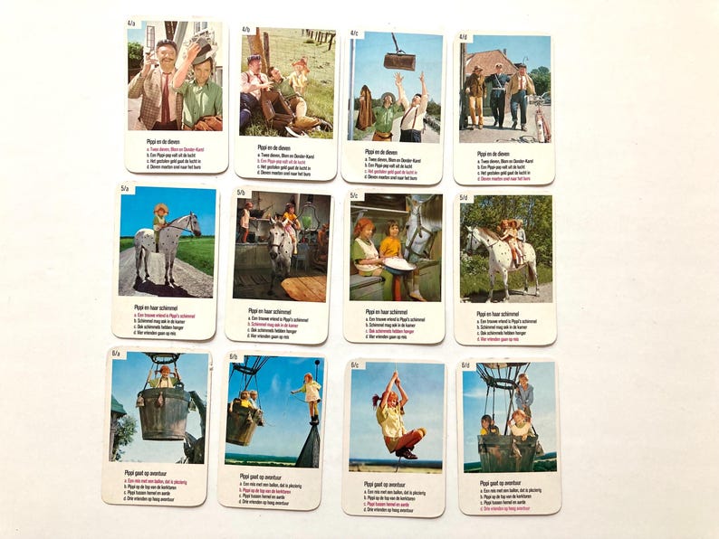 Op de afbeelding: Een verzameling vintage ruilkaarten met kleurrijke illustraties van sc&egrave;nes met mensen en dieren. Elke kaart heeft tekst in een vreemde taal. De kaarten zijn gerangschikt op een witte ondergrond.