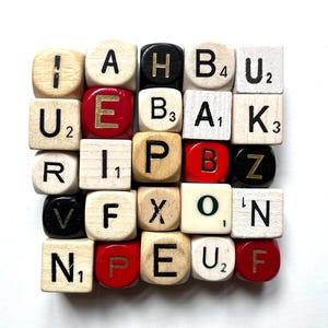 May include: A collection of wooden letter tiles, each with a letter and a point value. The tiles are in various colors, including natural wood, black, red, and white. The letters are in a variety of fonts.