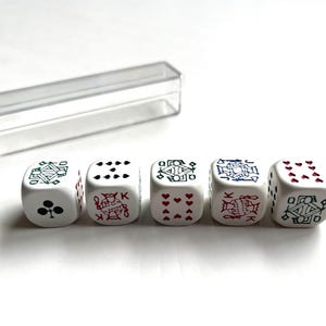 May include: Five white dice with playing card symbols and a clear plastic case. Each die features a different card suit or face card, including clubs, hearts, and diamonds. The dice are arranged in a row on a white surface.
