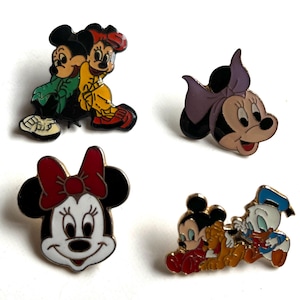 May include: Four enamel pins featuring Disney characters. Mickey and Minnie Mouse are depicted in various poses, including a pair embracing, Minnie with a purple bow, and Mickey with Donald Duck. The pins have vibrant colors and are set against a white background.
