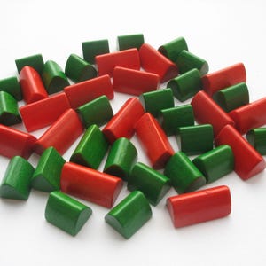 May include: A collection of wooden game pieces in red and green. The pieces are shaped like small houses with rounded tops.