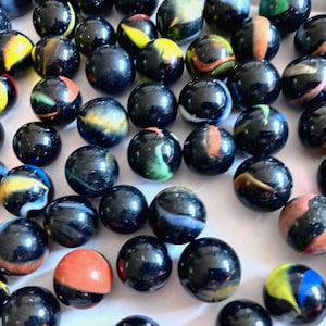 Op de afbeelding: Een verzameling zwarte knikkers met kleurrijke swirls en patronen. De knikkers zijn gerangschikt op een wit oppervlak.