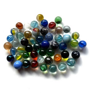 May include: A collection of numerous spherical glass marbles in a wide variety of colors and patterns. The assortment includes solid, translucent, and opaque glass spheres in shades of blue, green, red, yellow, black, white, and clear glass.