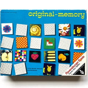 May include: A blue rectangular board game box titled original-memory. The front features a grid of twenty-two square tiles displaying various illustrations including a lion, strawberry, apple, flower, and patterns, with Ravensburger Spiele branding.