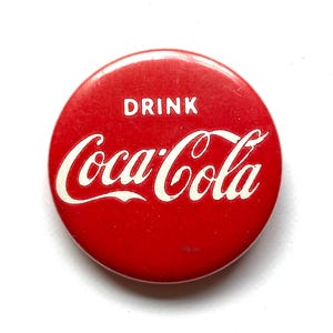 May include: Red round button with white text that reads "Drink Coca-Cola".