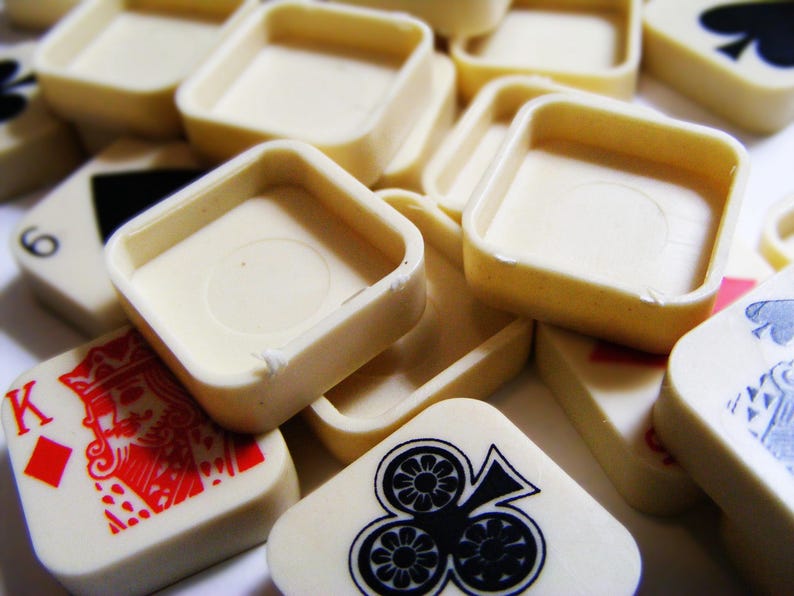 Pode incluir: Pe&ccedil;as de jogo e bandejas quadradas de cor marfim espalhadas. As pe&ccedil;as do jogo apresentam naipes e n&uacute;meros de cartas de jogar em vermelho e preto. As bandejas t&ecirc;m formato quadrado com cantos arredondados.