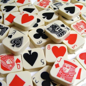 Pode incluir: Uma cole&ccedil;&atilde;o de pe&ccedil;as quadradas de cartas de jogar em branco sujo com s&iacute;mbolos de naipe vermelhos, pretos e brancos e figuras. As pe&ccedil;as est&atilde;o espalhadas, mostrando v&aacute;rios valores de cartas e naipes, incluindo espadas, cora&ccedil;&otilde;es, paus e ouros.