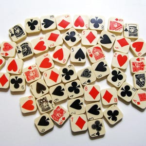 Pode incluir: Uma cole&ccedil;&atilde;o de pe&ccedil;as de jogo quadradas, branco sujo, com naipes e valores de cartas de jogar. As pe&ccedil;as exibem cora&ccedil;&otilde;es vermelhos, ouros, espadas e paus pretos, e figuras. Os n&uacute;meros e naipes s&atilde;o em preto e vermelho.
