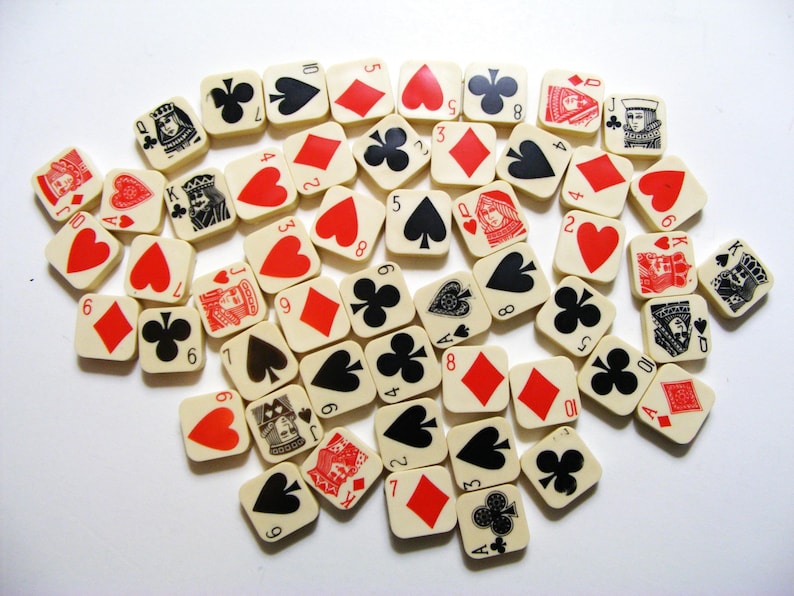 Pode incluir: Uma cole&ccedil;&atilde;o de pe&ccedil;as de jogo quadradas, branco sujo, com naipes e valores de cartas de jogar. As pe&ccedil;as exibem cora&ccedil;&otilde;es vermelhos, ouros, espadas e paus pretos, e figuras. Os n&uacute;meros e naipes s&atilde;o em preto e vermelho.