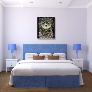 May include: A blue and white bedroom with a bed, two nightstands, and a painting of an owl above the bed. The owl is made of colorful dots and has yellow eyes.