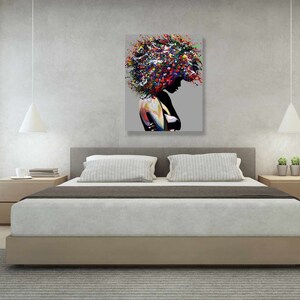 Puede incluir: Una pintura abstracta colorida de una persona con un gran peinado afro. La pintura es de estilo moderno y presenta una variedad de colores, incluyendo rojo, azul, verde y amarillo. La pintura est&aacute; colgada en una pared en un dormitorio.
