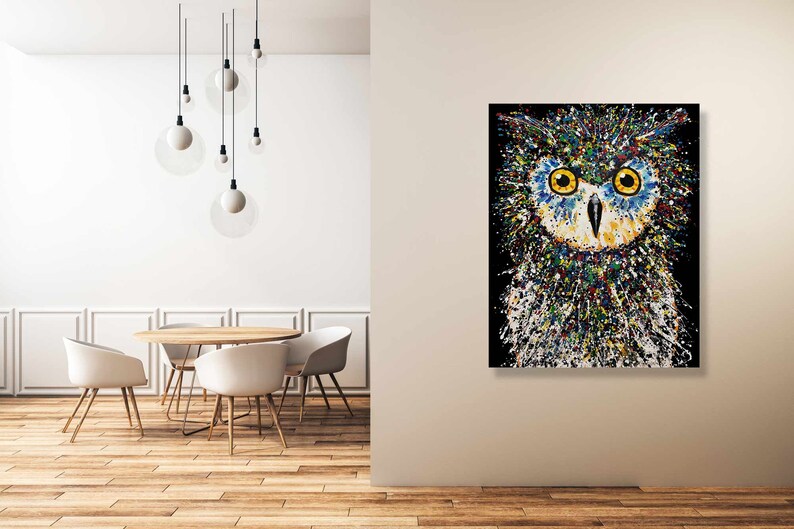 May include: A colorful abstract painting of an owl with yellow eyes. The owl is painted in a splatter style with a black background.