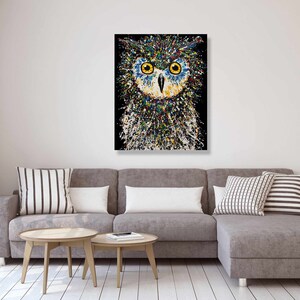 May include: A colorful abstract painting of an owl with yellow eyes on a black background.