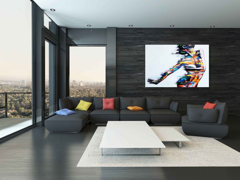 May include: A modern living room with a black sectional sofa, a white coffee table, and a large abstract painting of a person on a black wall.