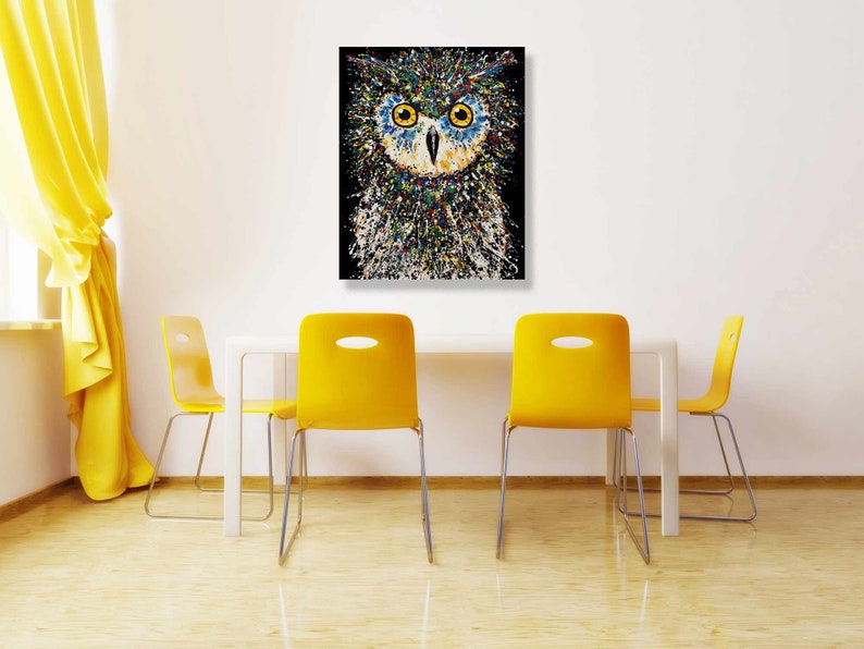 May include: A colorful abstract painting of an owl with blue eyes. The owl is painted in a splatter style with a black background.