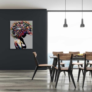 Puede incluir: Pintura abstracta de una mujer con el pelo de colores, colgada en una pared de un comedor con una mesa y sillas de madera.