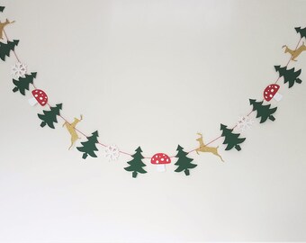 May include: A decorative garland with dark green felt Christmas trees, gold glitter reindeer, white snowflakes, and red and white mushroom shapes. The garland is strung on red thread, ideal for festive decorations.