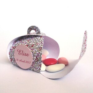 Pu&ograve; includere: Una scatola regalo bianca con un motivo floreale e un'etichetta rosa che dice "Elise 30 Avril 2017". La scatola &egrave; aperta e piena di confetti rosa e bianchi.