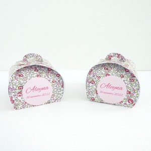 Pu&ograve; includere: Due scatole regalo bianche con un motivo floreale e dettagli rosa. Ogni scatola ha un cerchio rosa con il nome "Aleyma" e la data "16 settembre 2022".