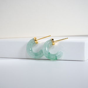 May include: A pair of jade green hoop earrings with gold accents. The earrings are small and delicate, and they would make a great gift for someone special.
