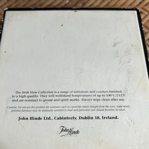 Pu&ograve; includere: Una scatola bianca con testo nero che descrive la collezione Irish View di sottopentole e sottobicchieri. Il testo indica che i prodotti resistono a temperature fino a 100 &deg;C/212 &deg;F e sono resistenti al grasso e alle macchie di alcol. La scatola include anche un avvertimento per non utilizzare i prodotti per utensili da forno. Il testo include anche il nome dell'azienda e la sua posizione: John Hinde Ltd., Cabinteely, Dublino 18, Irlanda.