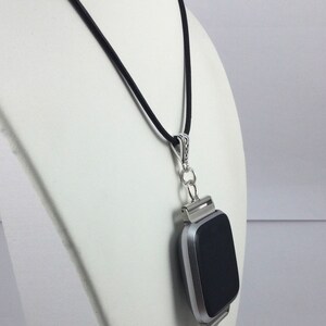 May include: A silver-toned smartwatch pendant necklace with a black screen, suspended from a black cord. The pendant features a cluster of blue crystal beads. The necklace is displayed on a white mannequin.