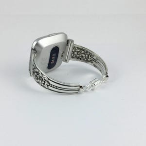 Pu&ograve; includere: Cinturino per orologio in argento con un design floreale ornato. Il cinturino &egrave; fatto per adattarsi a uno smartwatch di forma quadrata.