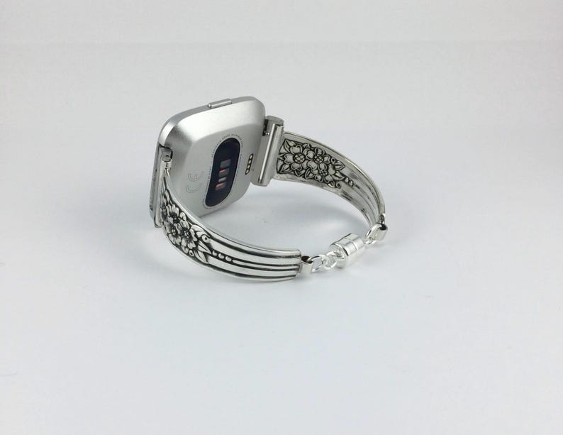Pu&ograve; includere: Cinturino per orologio in argento con un design floreale ornato. Il cinturino &egrave; fatto per adattarsi a uno smartwatch di forma quadrata.