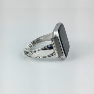 Peut inclure: Un bracelet de montre argent&eacute; fabriqu&eacute; &agrave; partir d'une pi&egrave;ce de couverts r&eacute;utilis&eacute;e. Le bracelet est attach&eacute; &agrave; une montre intelligente argent&eacute;e avec un &eacute;cran noir.