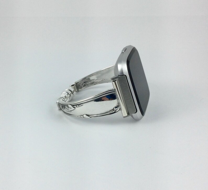 Peut inclure: Un bracelet de montre argent&eacute; fabriqu&eacute; &agrave; partir d'une pi&egrave;ce de couverts r&eacute;utilis&eacute;e. Le bracelet est attach&eacute; &agrave; une montre intelligente argent&eacute;e avec un &eacute;cran noir.