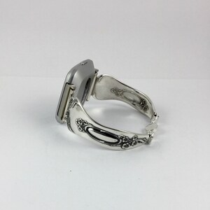 May include: A silver watch with a square face and a unique, ornate, silver spoon-shaped band.