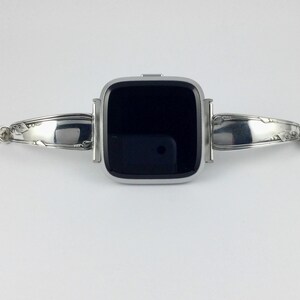 Peut inclure: Un bracelet de montre argent&eacute; fabriqu&eacute; &agrave; partir d'argenterie r&eacute;utilis&eacute;e. Le bracelet est con&ccedil;u pour s'adapter &agrave; une montre connect&eacute;e de forme carr&eacute;e. Le bracelet pr&eacute;sente un design d&eacute;coratif aux extr&eacute;mit&eacute;s.