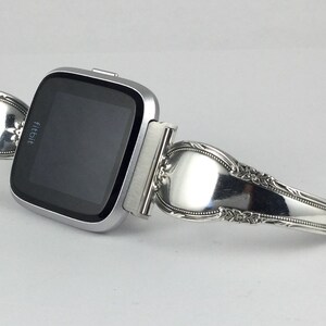 May include: A silver Fitbit smartwatch with a custom-made band crafted from a vintage silverware spoon.