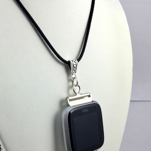 May include: A silver Fitbit smartwatch pendant necklace with a black cord. The watch has a black screen and is accented with a cluster of blue beads. The necklace is displayed on a white mannequin.