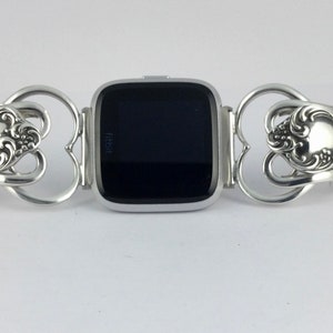 Puede incluir: Una pulsera de reloj plateada hecha de cubiertos reutilizados. La pulsera est&aacute; dise&ntilde;ada para adaptarse a un reloj Fitbit. La pulsera presenta un dise&ntilde;o en forma de coraz&oacute;n con detalles ornamentados.