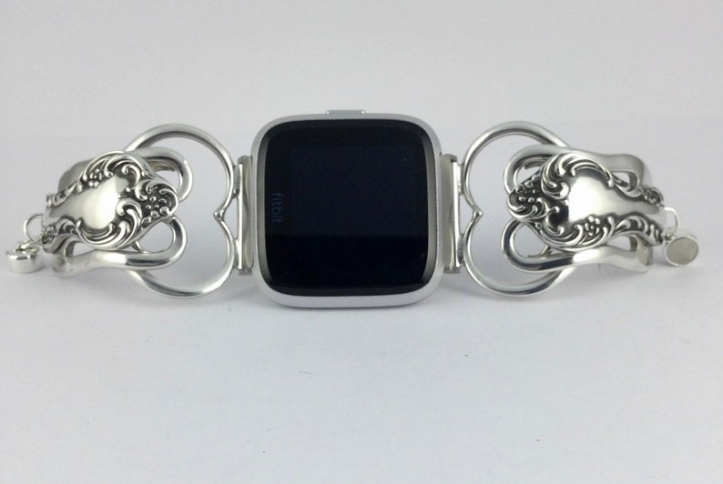 Puede incluir: Una pulsera de reloj plateada hecha de cubiertos reutilizados. La pulsera est&aacute; dise&ntilde;ada para adaptarse a un reloj Fitbit. La pulsera presenta un dise&ntilde;o en forma de coraz&oacute;n con detalles ornamentados.