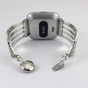 Pu&ograve; includere: Cinturino per orologio in argento con un design decorato. Il cinturino &egrave; in metallo e ha una chiusura a scatto. Il cinturino &egrave; compatibile con uno smartwatch di forma quadrata.