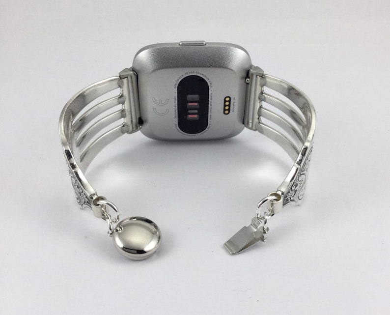 Pu&ograve; includere: Cinturino per orologio in argento con un design decorato. Il cinturino &egrave; in metallo e ha una chiusura a scatto. Il cinturino &egrave; compatibile con uno smartwatch di forma quadrata.