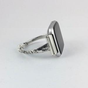 May include: A silver watch band with an ornate floral design. The watch face is square and black.