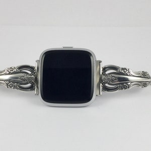 May include: A silver smartwatch with a black screen, attached to a silver watch band made from a repurposed silverware handle.