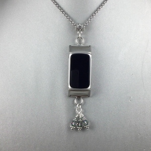 May include: A silver chain necklace with a black face watch pendant and a silver charm with three iridescent beads.