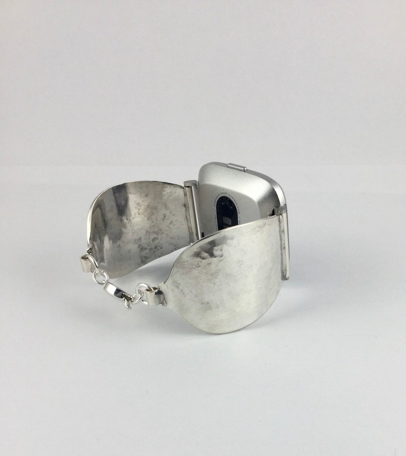May include: A silver watch with a hammered metal band. The watch face is square and has a silver finish.