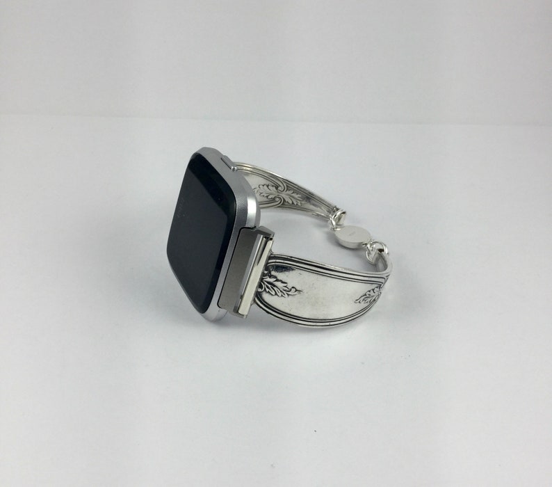 May include: A silver smartwatch with a black screen is attached to a silver bracelet made from a repurposed spoon.
