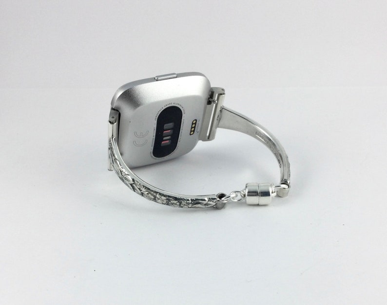 May include: Silver smartwatch with a textured silver band. The band has a magnetic clasp.