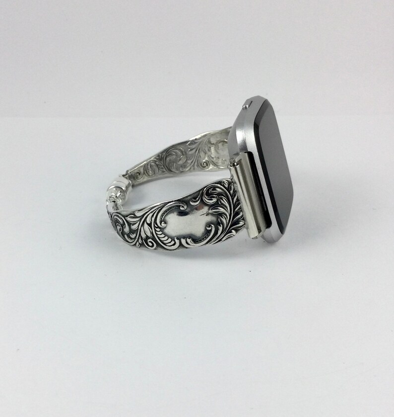 Puede incluir: Una pulsera de reloj plateada con un dise&ntilde;o floral adornado. La pulsera est&aacute; hecha de metal y tiene un acabado pulido.