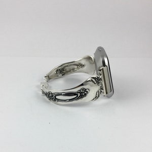 May include: A silver watch with a square face and a decorative spoon-shaped band.