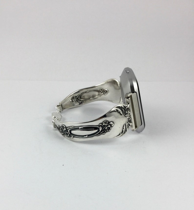 May include: A silver watch with a square face and a decorative spoon-shaped band.