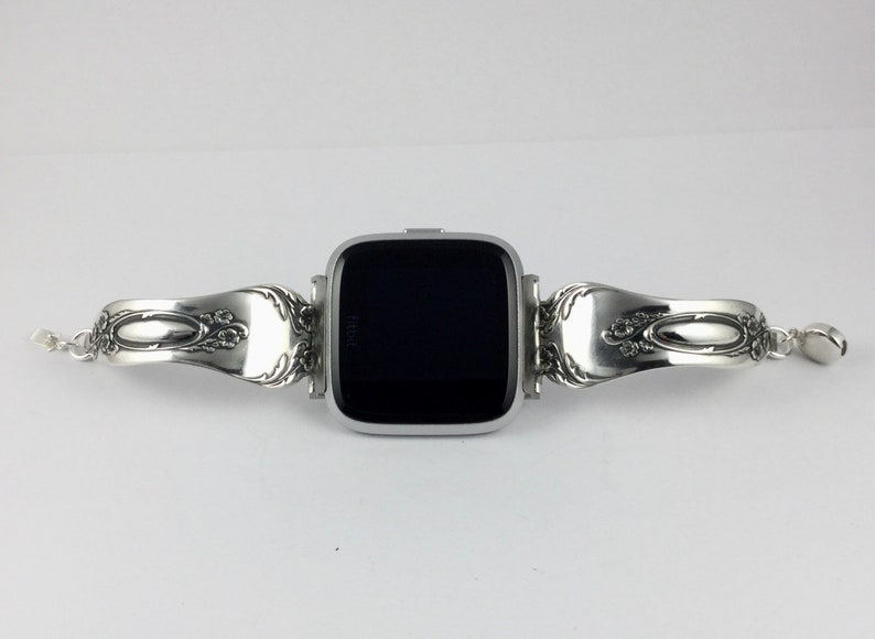 May include: A silver smartwatch with a black screen is attached to a silver bracelet made from two vintage silverware spoons.